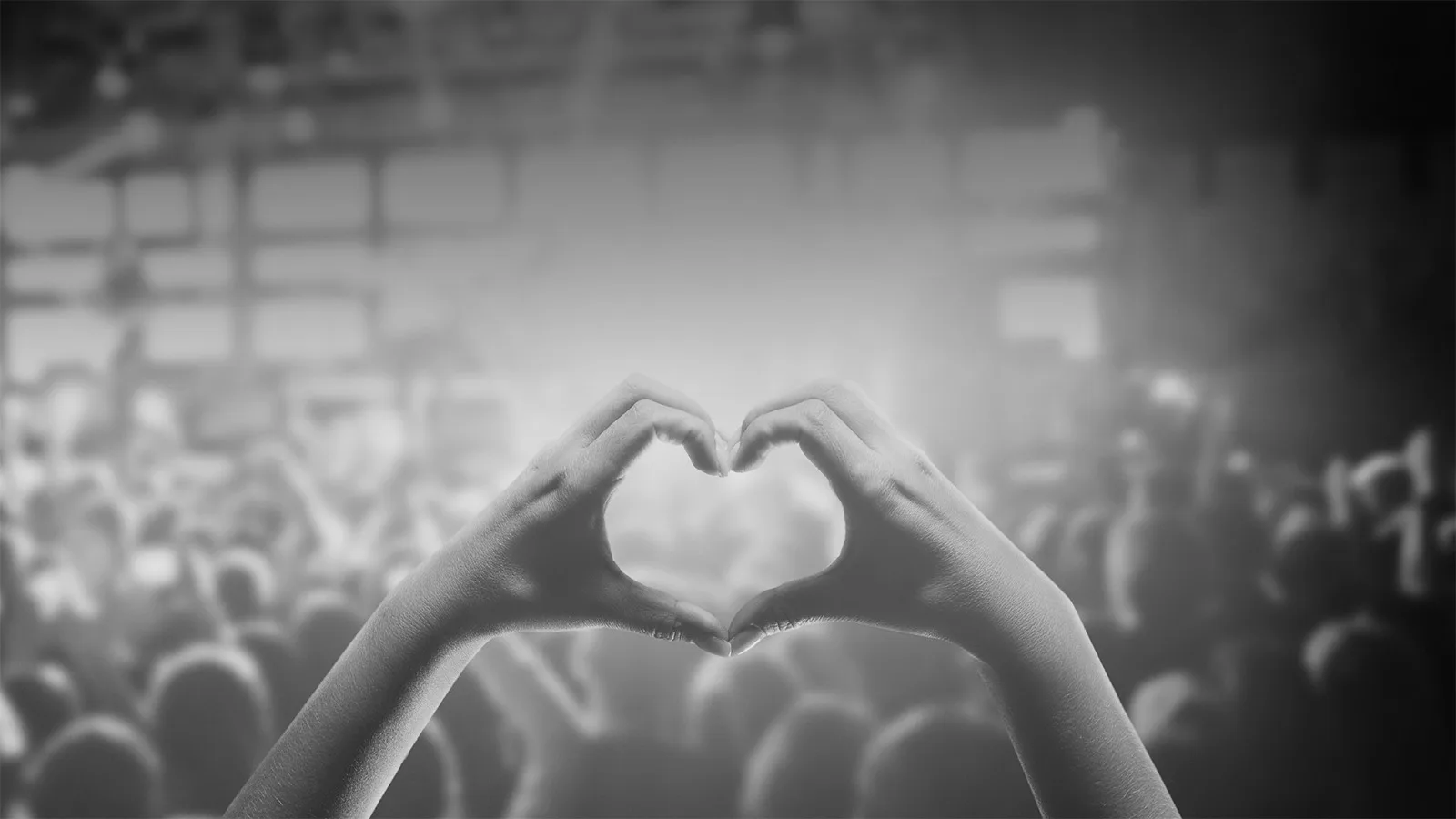 Två händer formar ett hjärta i ett publikhav